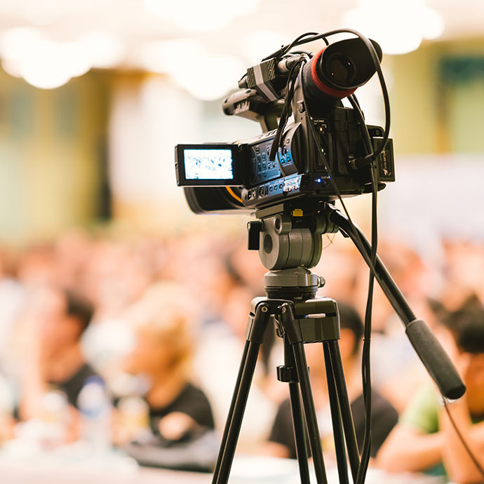 A camera live-streaming an in-person audience for a hybrid event