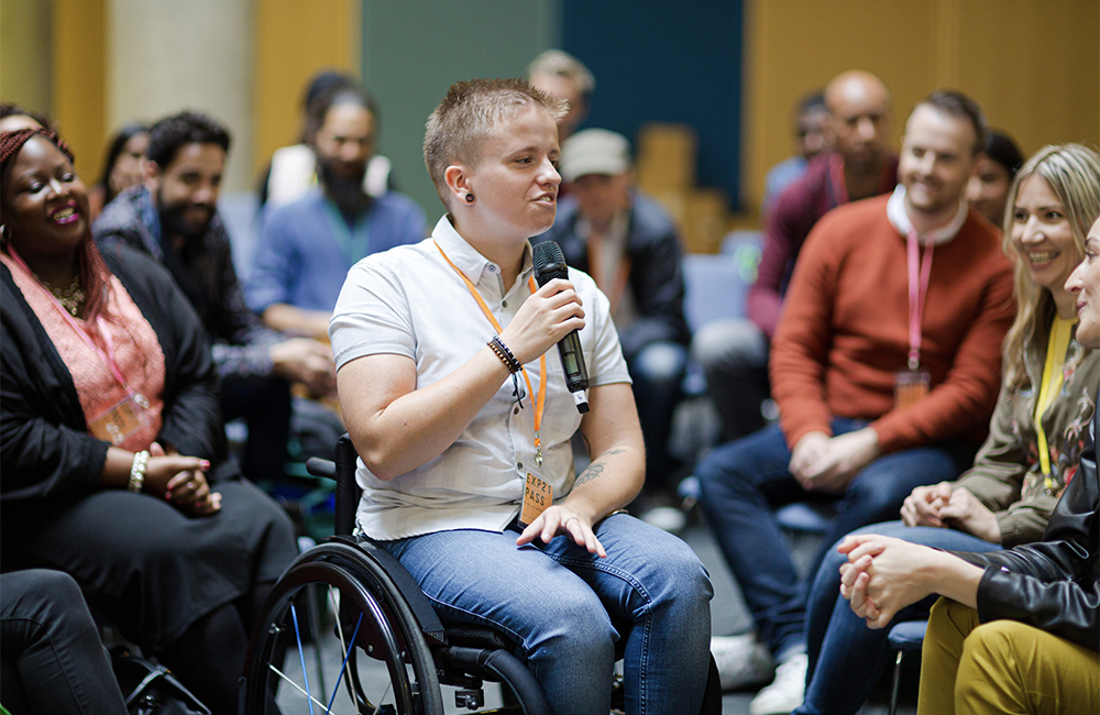 person in a wheelchair holding a microphone at DEI events